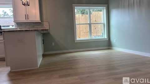 A kitchen with white cabinets and a window with wooden fence outside.