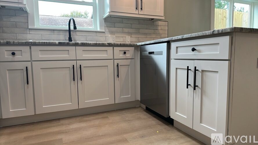 A kitchen with white cabinets and a black faucet.