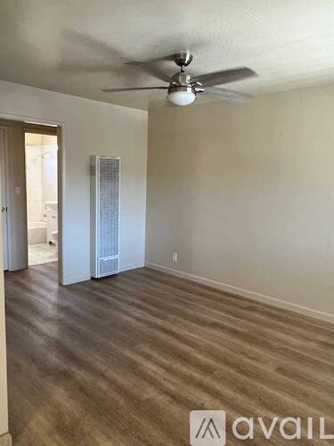 A room with a ceiling fan and wooden flooring.