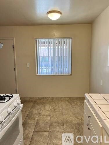 A kitchen with a stove top oven and a window with blinds.