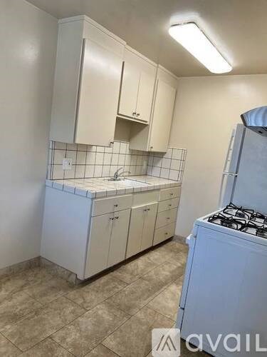 A kitchen with white cabinets and a tiled backsplash.