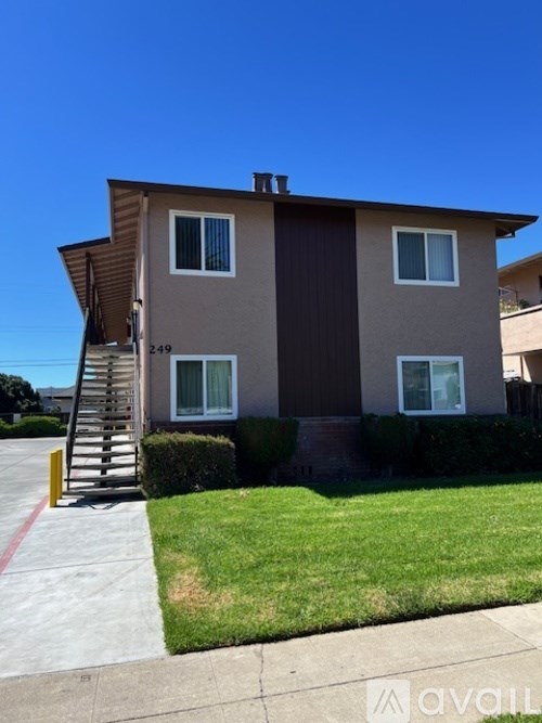 A two-story house with a brown and beige exterior and a small front yard.