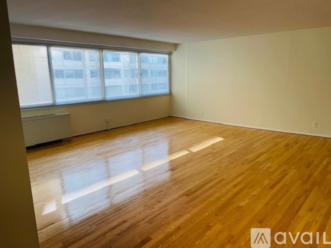 A spacious room with wooden flooring and large windows.