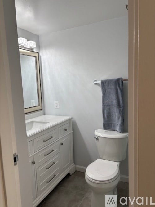 A white toilet in a bathroom with a white sink and a mirror.