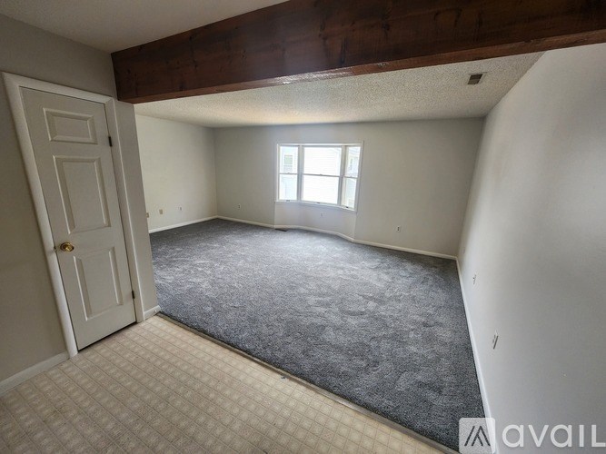 A room with a door, a window, and a carpeted floor.