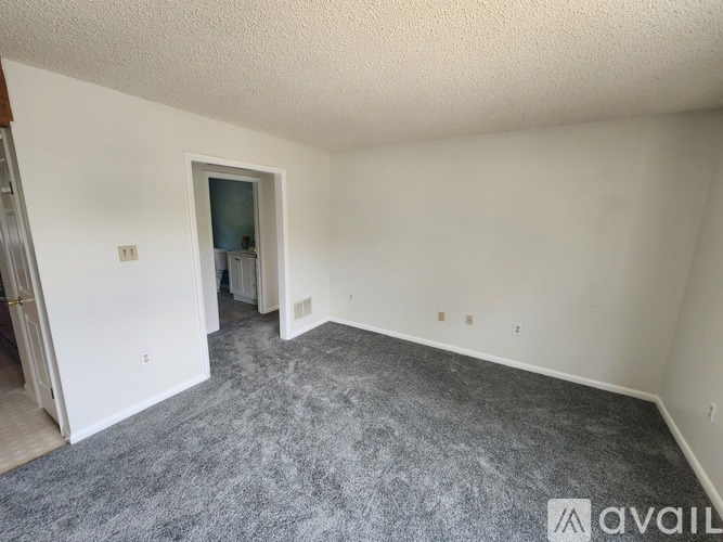 A room with a grey carpet and white walls is available for rent.