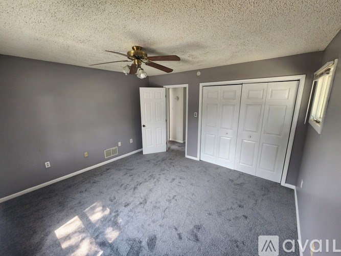 A room with a ceiling fan and two doors.