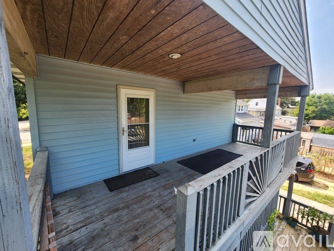 A wooden deck with a black mat in front of a blue house.