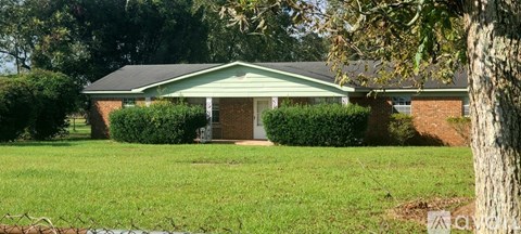 A house with a green lawn and a tree in front.