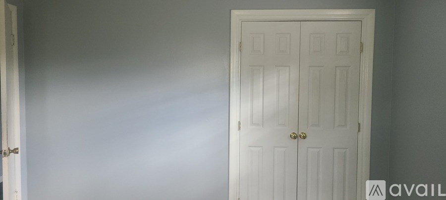 A white door with a gold handle is in a room with white walls.
