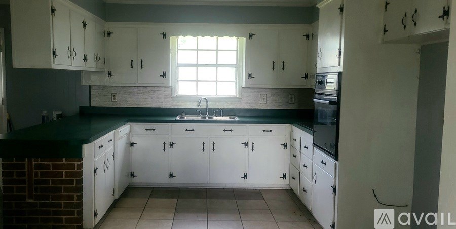 A kitchen with white cabinets and a green countertop.