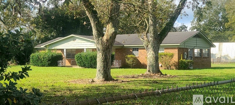 A house with a green lawn and trees in front of it.