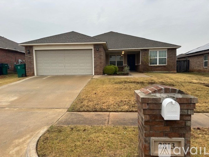 A house with a garage door and a brick pillar in front of it.