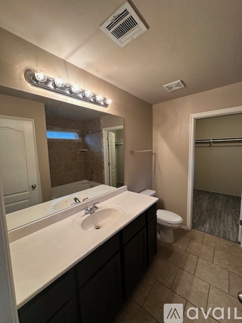 A bathroom with a white sink and a mirror with lights above it.