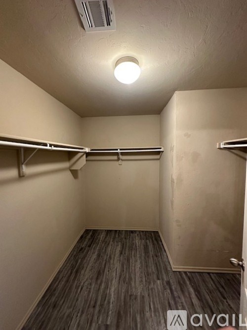 A small, empty room with a light on the ceiling and a wooden floor.
