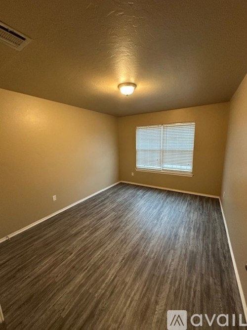 A room with wooden flooring and a window with blinds.