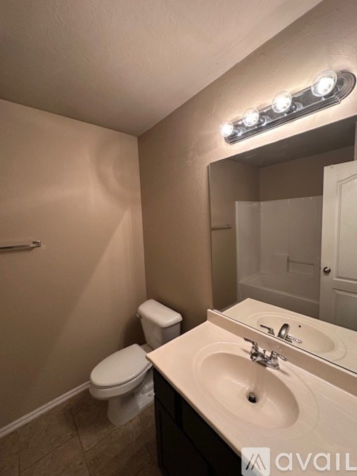 A bathroom with a toilet, sink, and mirror.