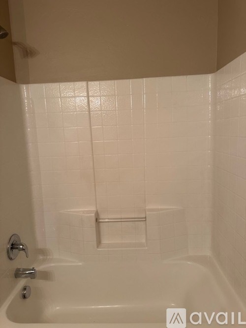 A white bathtub with a shower head and a faucet.