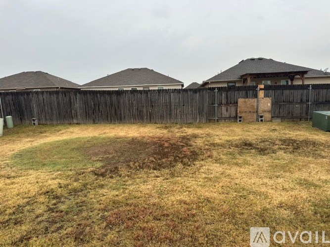 A backyard with a wooden fence and a grassy area.