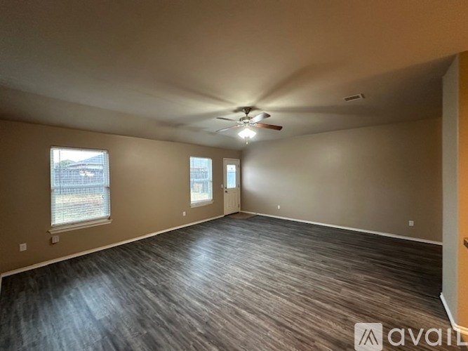 A spacious room with a ceiling fan and wood flooring.