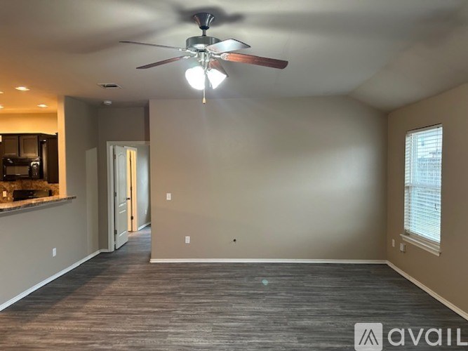 A spacious room with a ceiling fan and a window with blinds.