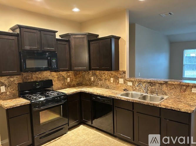 A kitchen with dark brown cabinets and a granite countertop.
