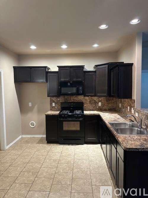 A kitchen with black cabinets and a beige floor.
