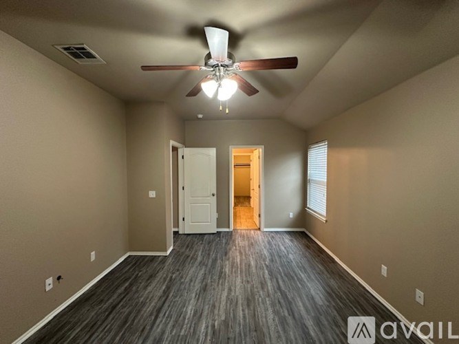 A spacious room with a ceiling fan and wooden flooring.