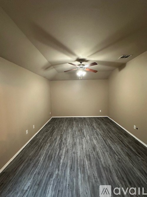 A room with a ceiling fan and wooden flooring.