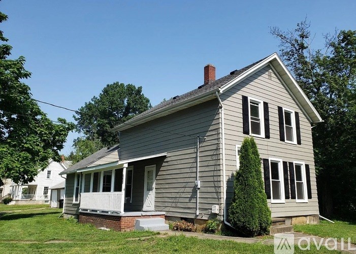 A house with a grey siding and a white porch.