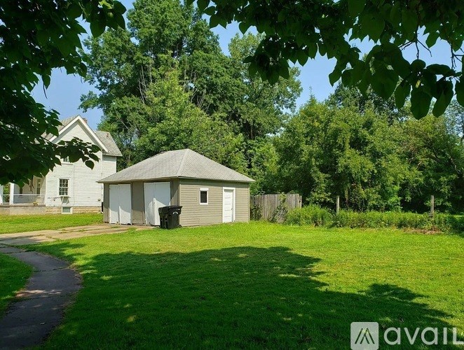 A small building with a grey roof is surrounded by greenery.