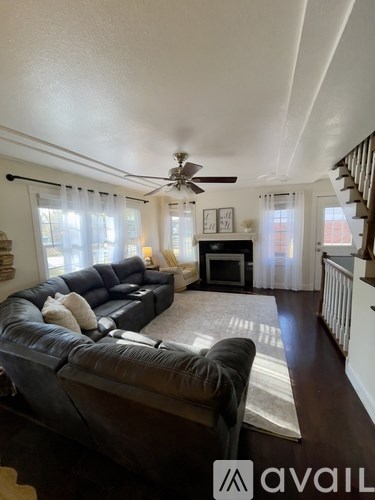 A living room with a couch, a fireplace, and a ceiling fan.