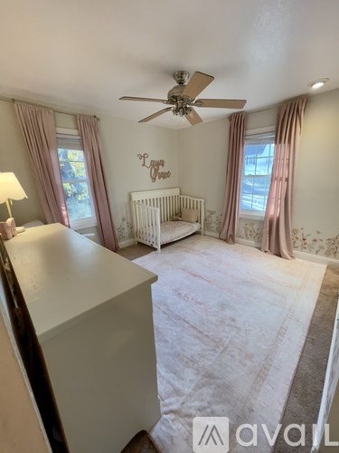 A baby's room with a white crib and a ceiling fan.