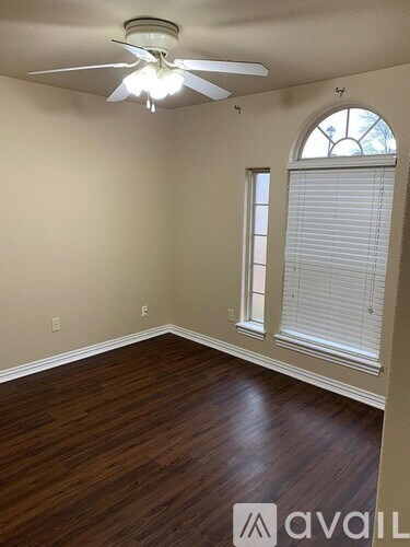 A room with a ceiling fan and wooden flooring.