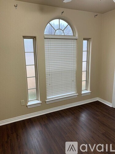 A room with wooden floors and three windows.