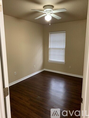 A room with a ceiling fan and a window with blinds.