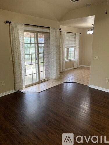 A room with wooden floors and a window with curtains.