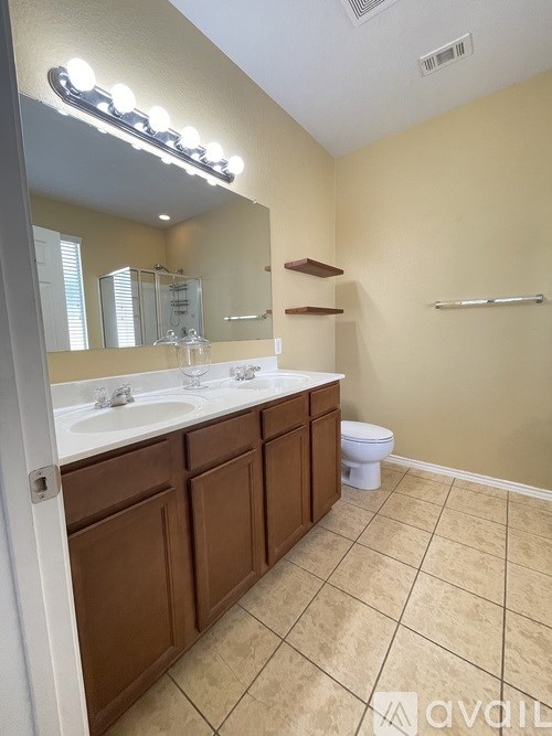 A bathroom with a white sink and brown cabinets.