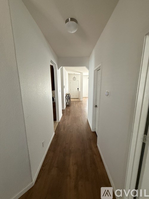 A long hallway with white walls and wood flooring.