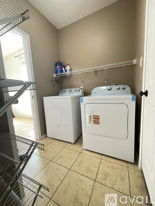 A laundry room with two washers and a shelf with cleaning supplies.
