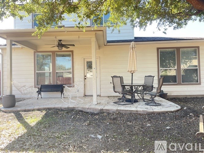 A patio with a table and chairs is in front of a house.