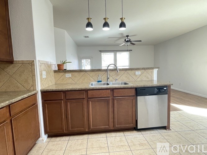 A kitchen with brown cabinets and a black dishwasher.