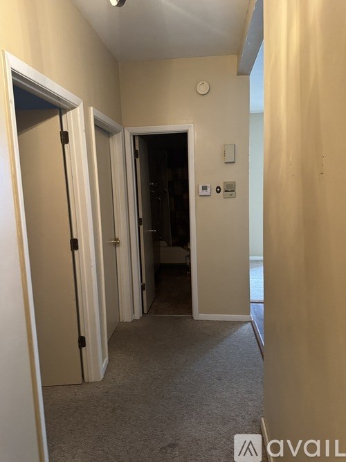 A hallway with a carpeted floor and a door on the left.