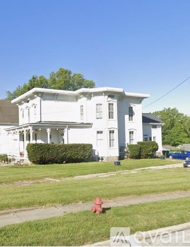 A white house with a red fire hydrant in front of it.