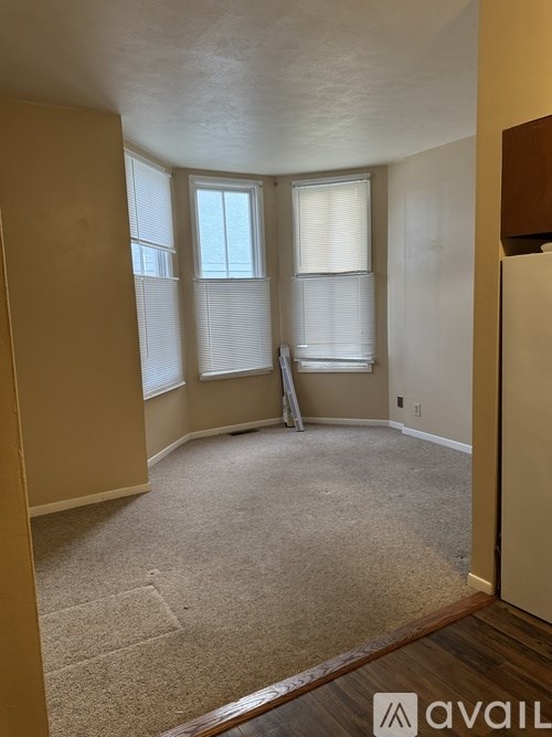 A room with a carpeted floor and a window with blinds.