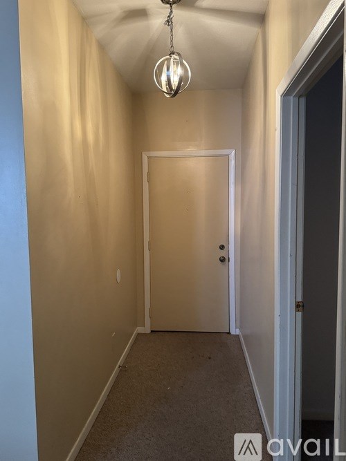 A hallway with a door and a light hanging from the ceiling.
