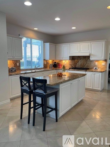 A kitchen with white cabinets and a granite countertop.