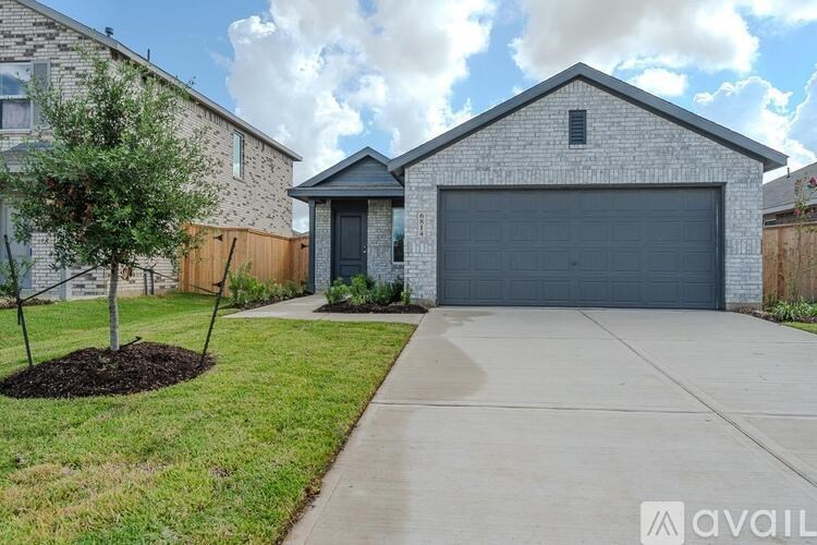 A house with a grey garage door and a tree in front.