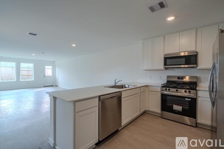 A kitchen with white cabinets and stainless steel appliances is available for rent.