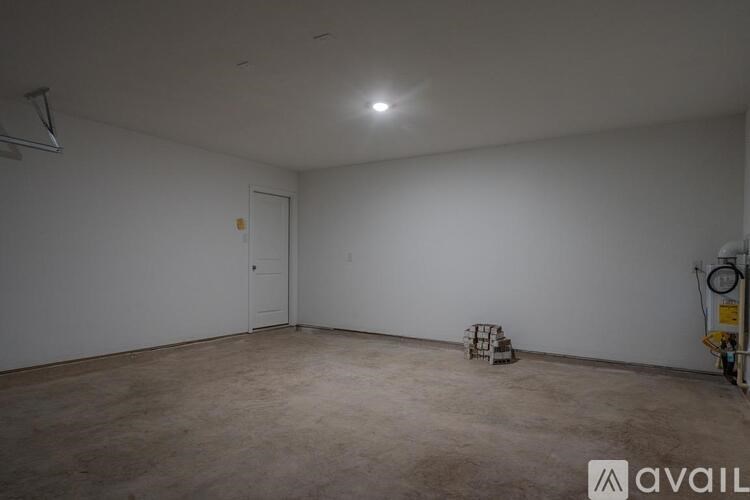 A large empty room with a door and a wall-mounted fan.